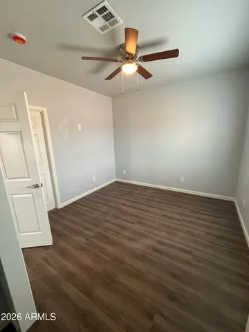 an empty room with wooden floor fan and windows