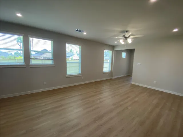 an empty room with wooden floor and windows