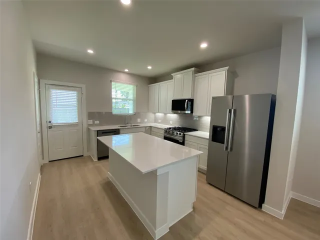 a large kitchen with stainless steel appliances granite countertop a sink a refrigerator and a stove top oven