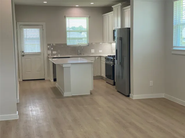 a kitchen with a sink cabinets stainless steel appliances and a window