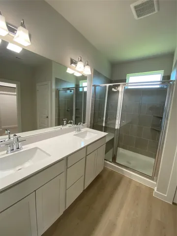 a bathroom with a double vanity sink mirror and shower