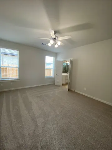 an empty room with windows and ceiling fan