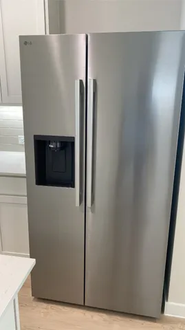 a view of a refrigerator in kitchen and an empty room