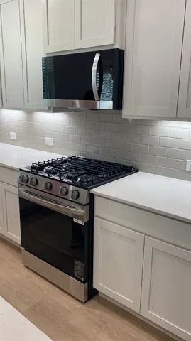 a kitchen with microwave cabinets and stove top oven
