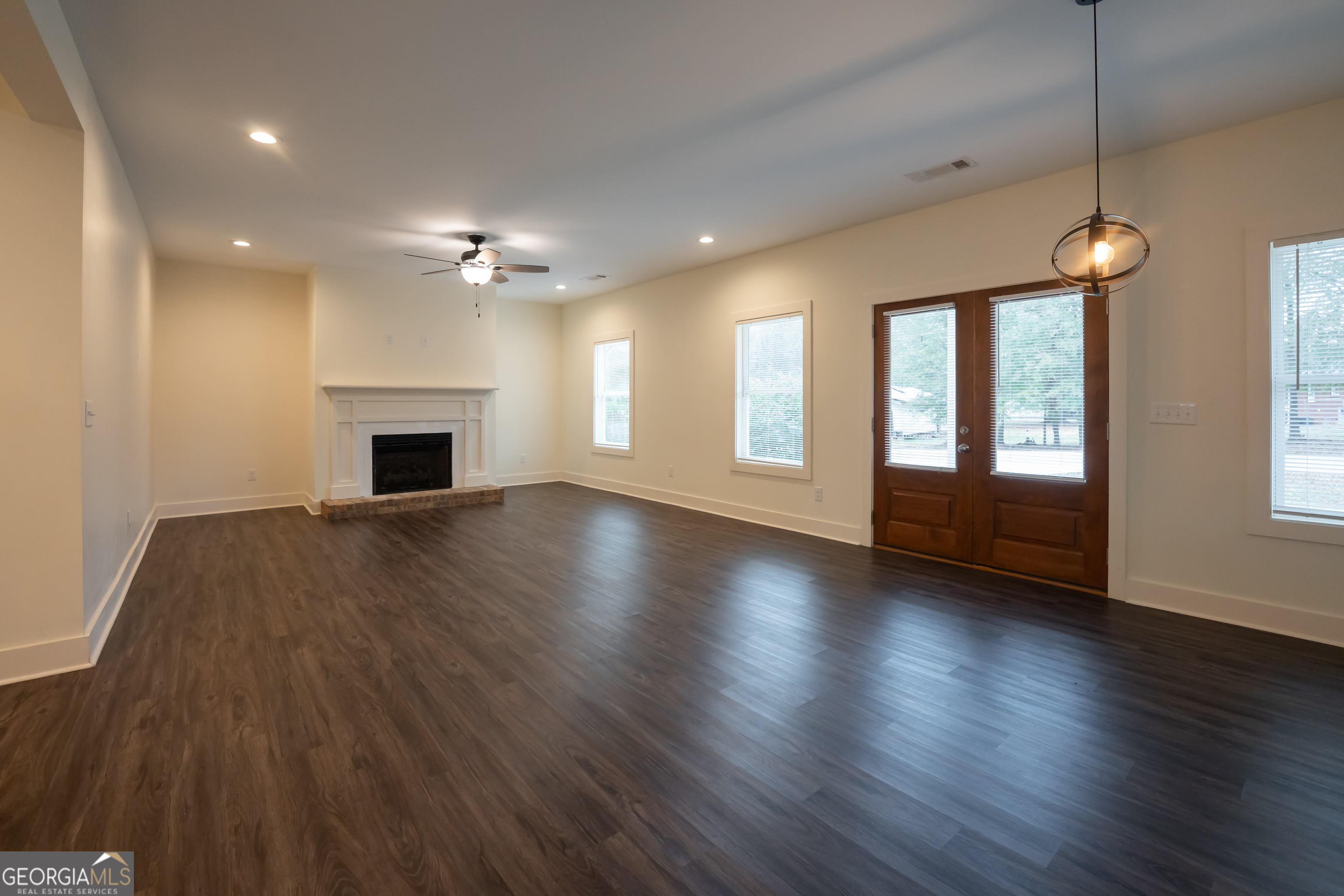 1000 Bell Circle Madison, GA 30650 - Photo 5 of 21 an empty room with wooden floor fireplace and windows