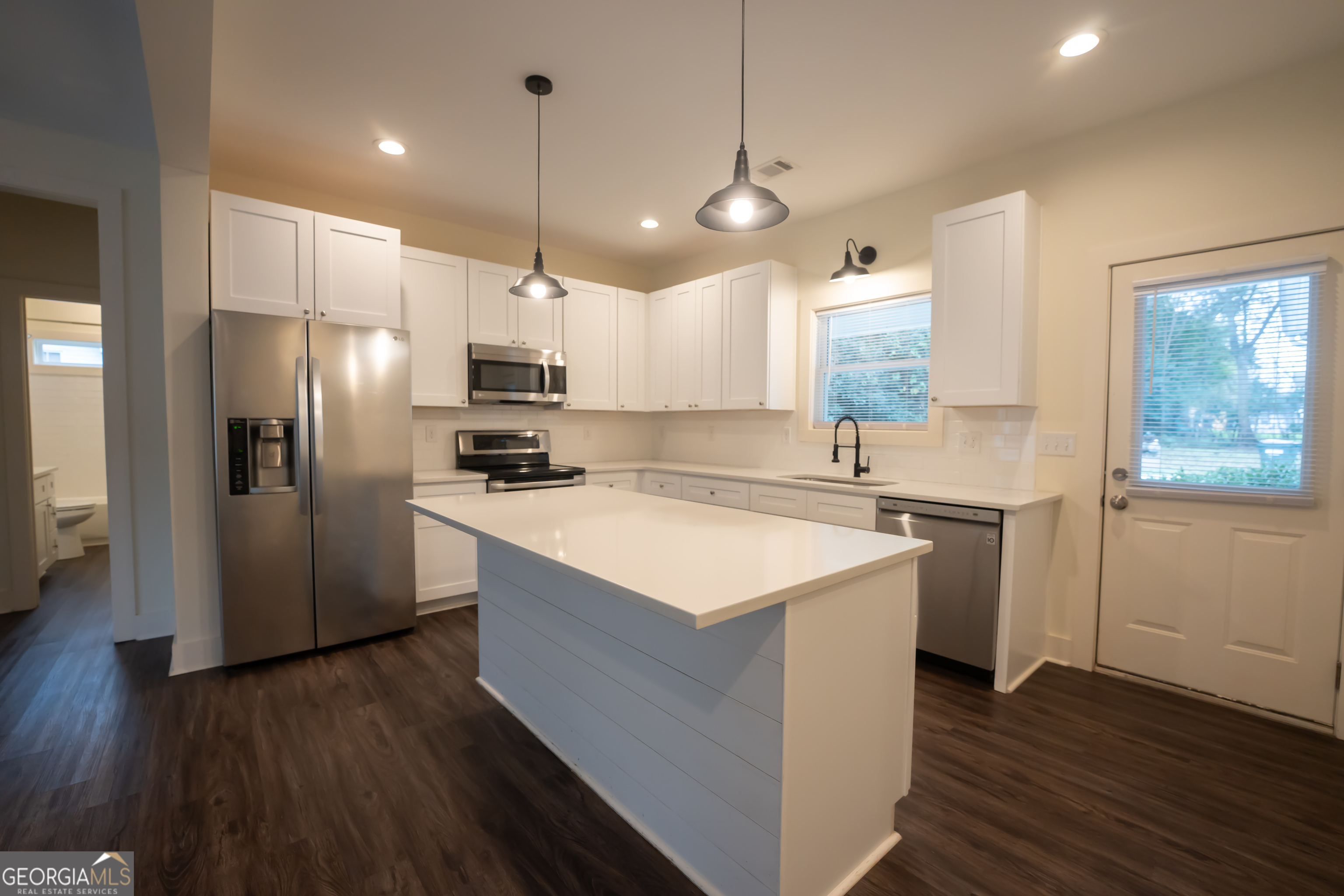 1000 Bell Circle Madison, GA 30650 - Photo 7 of 21 a kitchen with kitchen island a sink stainless steel appliances and wooden floor