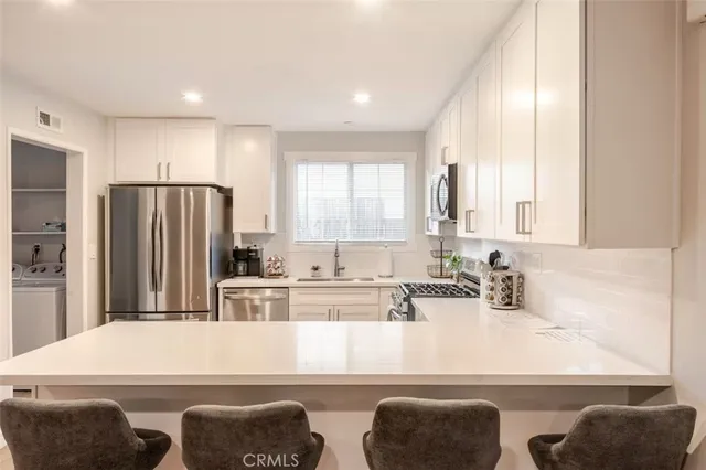 a kitchen with kitchen island white cabinets and stainless steel appliances