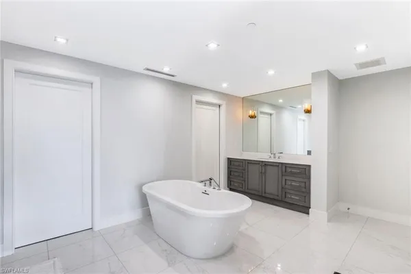 a bathroom with a bathtub a sink a mirror a toilet a window and vanity