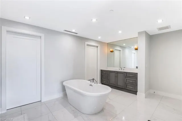 a bathroom with a bathtub a sink a mirror a toilet a window and vanity