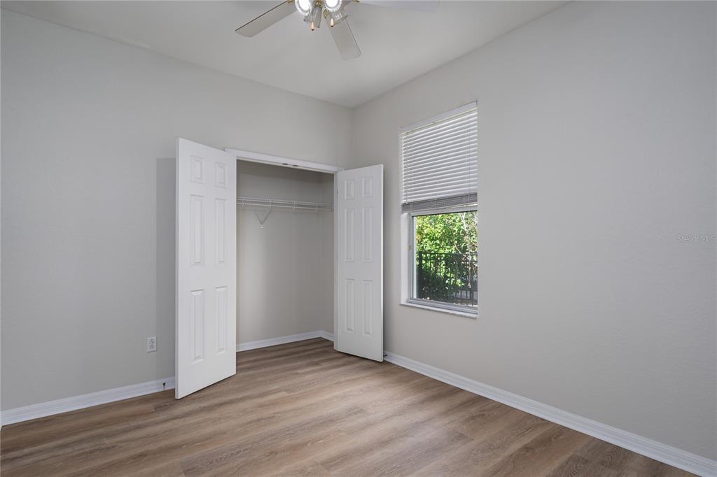 4420 85th Ave Circle East Parrish, FL 34219 - Photo 24 of 40 an empty room with wooden floor chandelier fan and windows