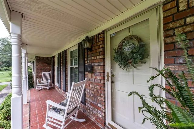 a porch with chairs and potted plant