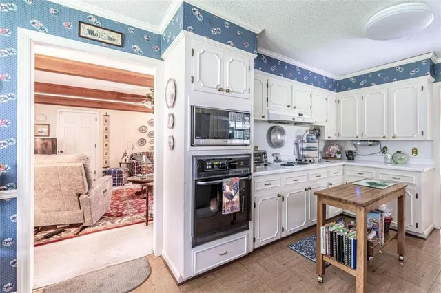 a kitchen with stainless steel appliances granite countertop a stove a refrigerator and white cabinets with wooden floor