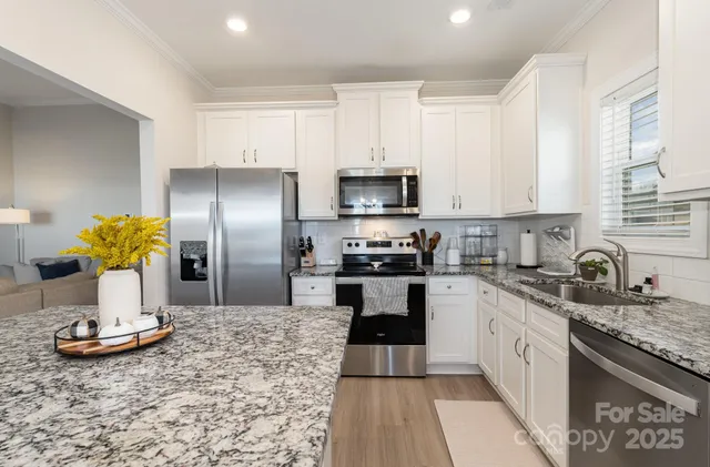 a kitchen with kitchen island granite countertop stainless steel appliances a sink dishwasher a refrigerator a stove top oven and a granite counter tops
