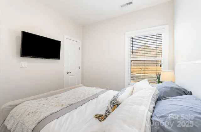 a bedroom with a bed a flat screen tv and a window