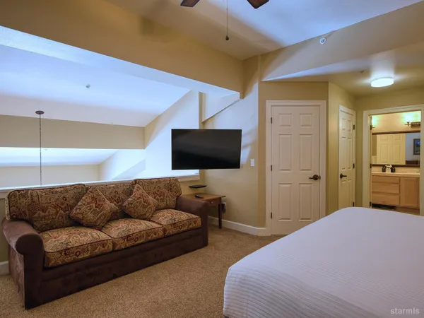 a bedroom with a bed and a flat tv screen on dresser
