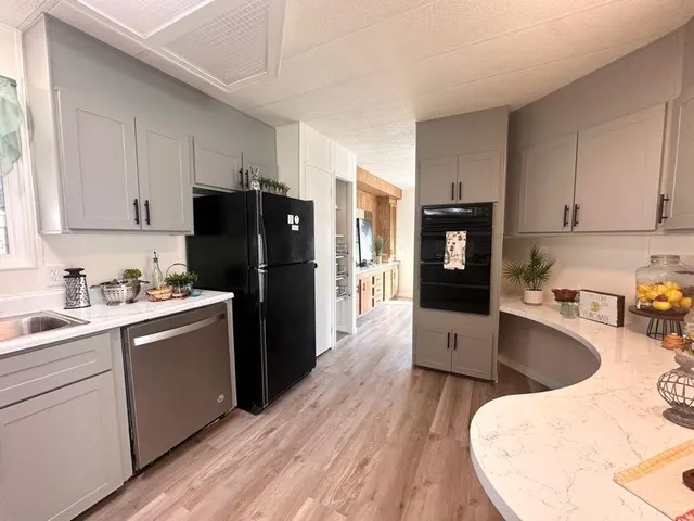 a kitchen with granite countertop a refrigerator a sink dishwasher a stove top oven a refrigerator and cabinets with wooden floor