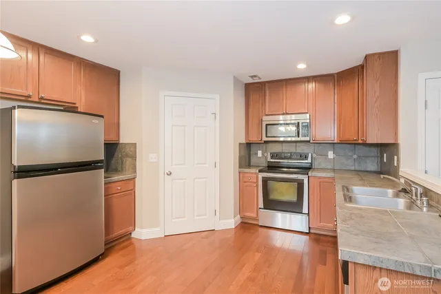 a kitchen with stainless steel appliances granite countertop a refrigerator sink and stove