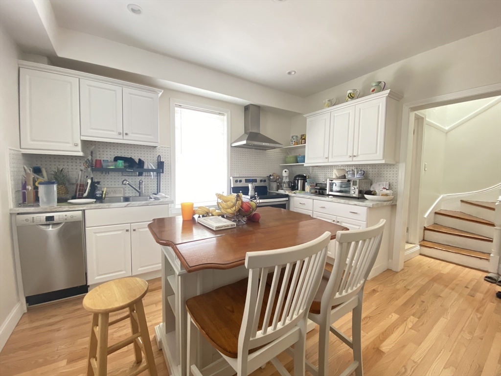 1 Minton Street, Unit 2 Boston, MA 02130 - Photo 4 of 12 a kitchen with stainless steel appliances granite countertop a stove a sink a refrigerator and white cabinets with wooden floor