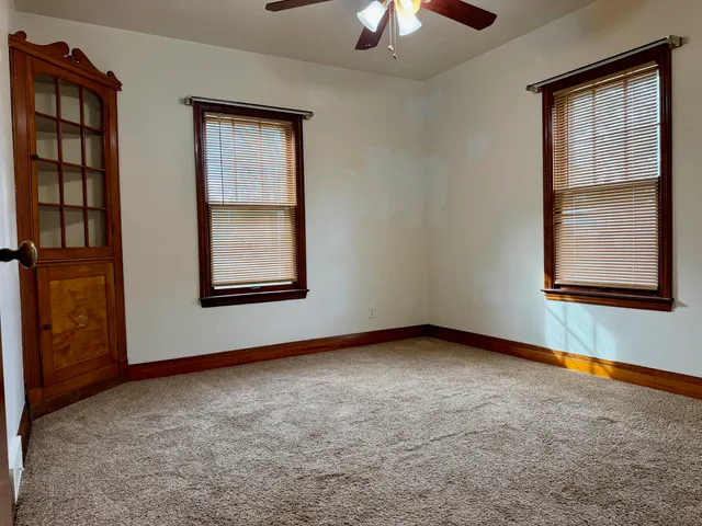 an empty room with windows and chandelier fan