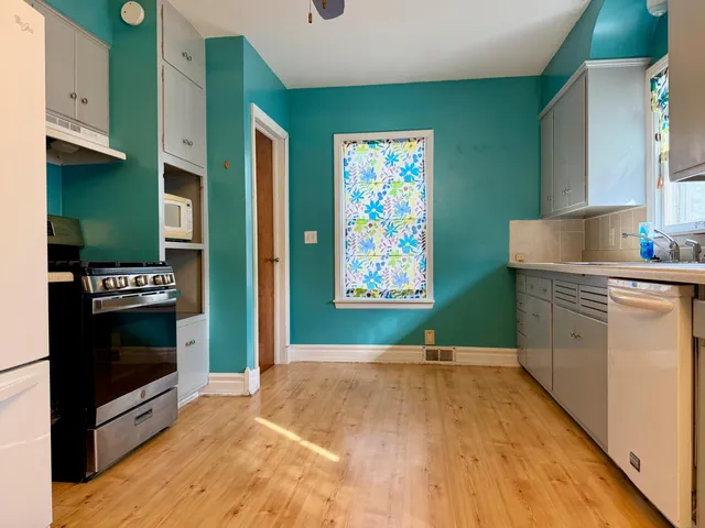 a kitchen with stainless steel appliances a stove top oven a refrigerator a sink and dishwasher with wooden floor