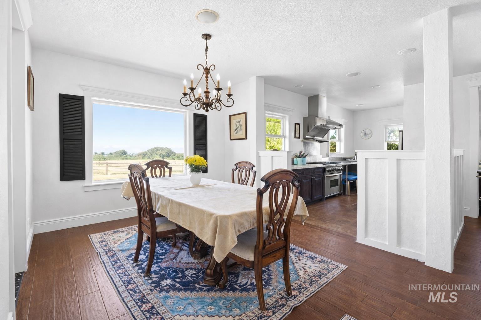 20169 Hoskins Road Caldwell, ID 83607 - Photo 23 of 46 Dining space with dark wood-style flooring, healthy amount of natural light, a chandelier, and a textured ceiling