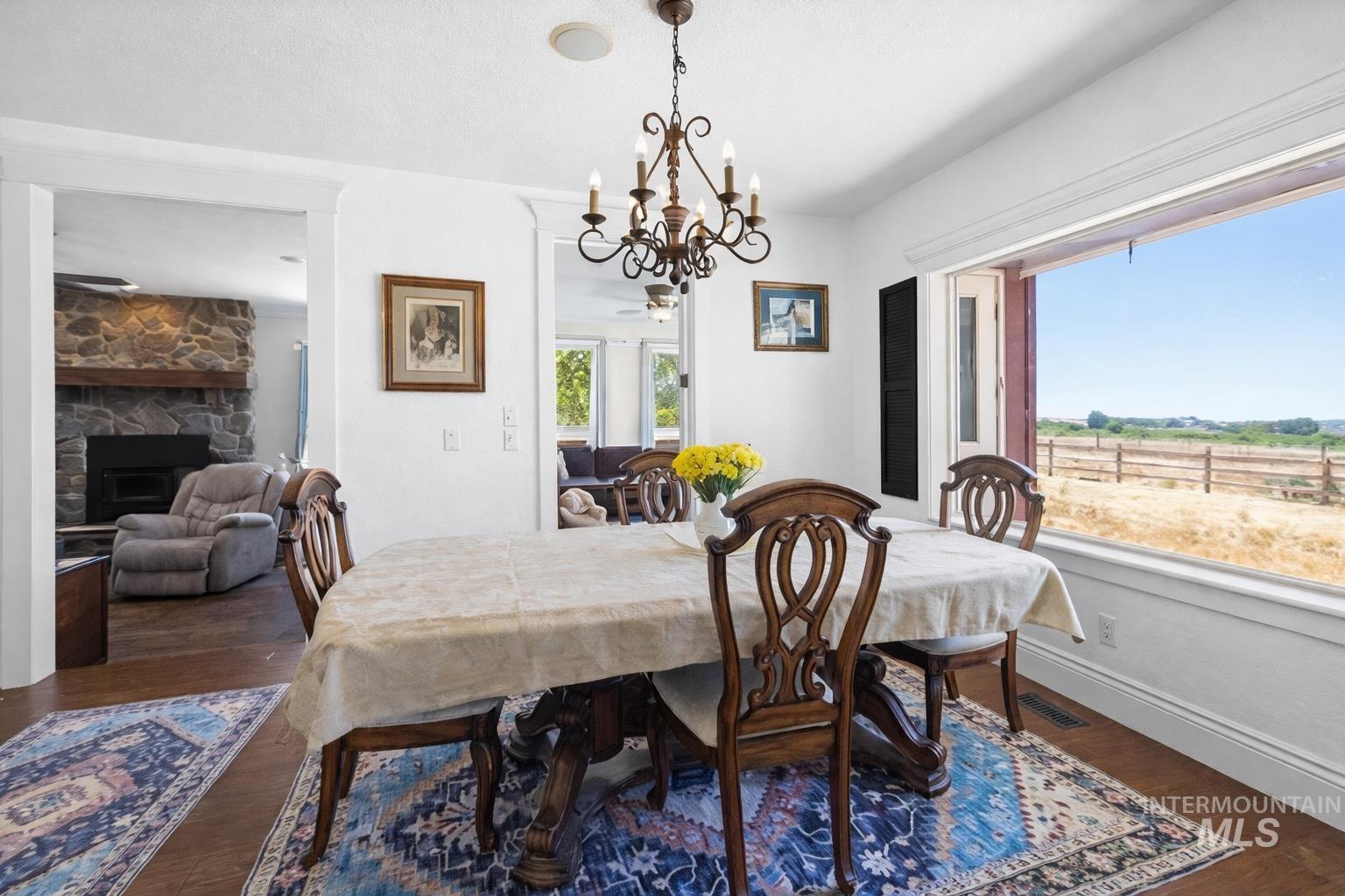 20169 Hoskins Road Caldwell, ID 83607 - Photo 24 of 46 Dining area featuring dark wood-type flooring, a chandelier, and a stone fireplace