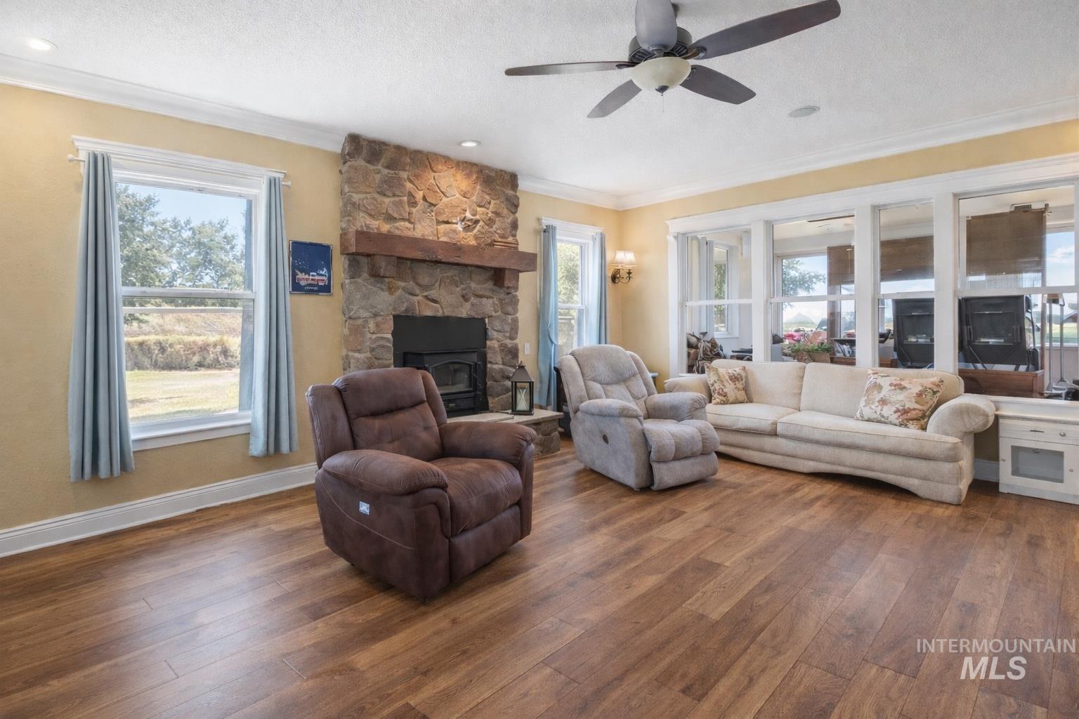 20169 Hoskins Road Caldwell, ID 83607 - Photo 26 of 46 Living area with hardwood / wood-style flooring, ceiling fan, crown molding, a textured ceiling, and a fireplace