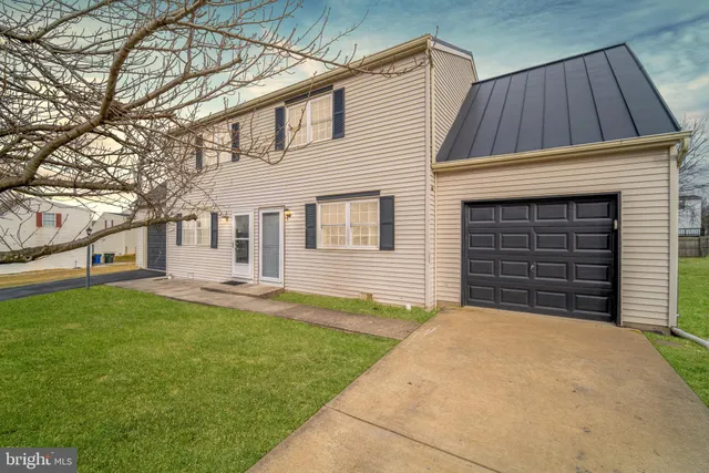 a view of a house with a small yard and a large tree