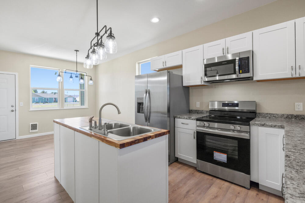 330 North Elm Street Merrill, OR 97633 - Photo 18 of 23 a kitchen with stainless steel appliances granite countertop a sink stove a refrigerator and microwave with wooden floor