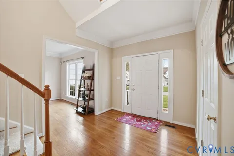 a view of an empty room with wooden floor and stairs