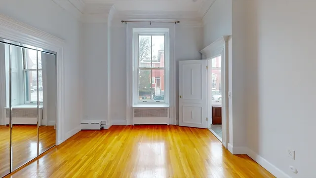 a view of empty room with wooden floor and windows