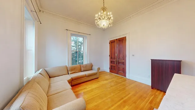a bedroom with a bed chandelier and a window