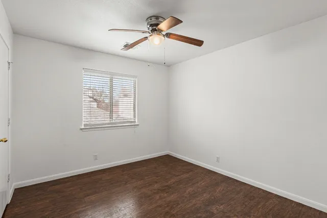 an empty room with wooden floor and ceiling fan