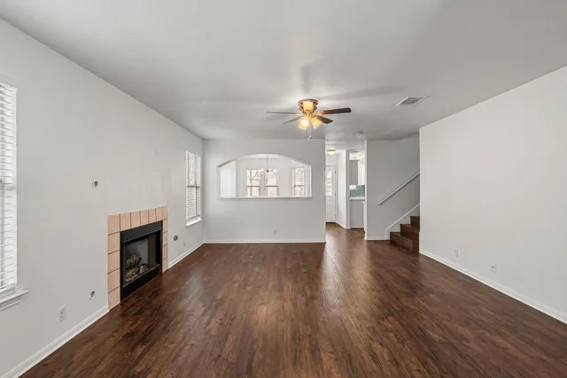 an empty room with wooden floor fireplace and windows