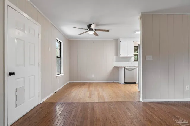 an empty room with wooden floor ceiling fan and windows