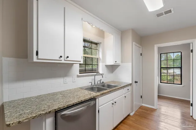 a kitchen with granite countertop white cabinets and a sink