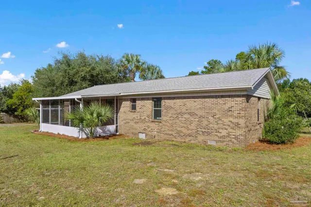 a front view of house with yard and trees in the background