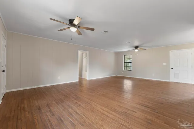a view of empty room with wooden floor and ceiling fan