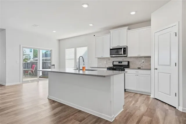 a kitchen with stainless steel appliances granite countertop white cabinets granite counter tops and a wooden floors