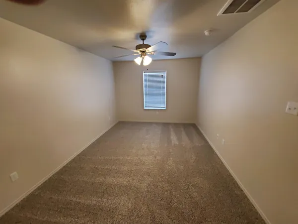 an empty room with a fan & a window