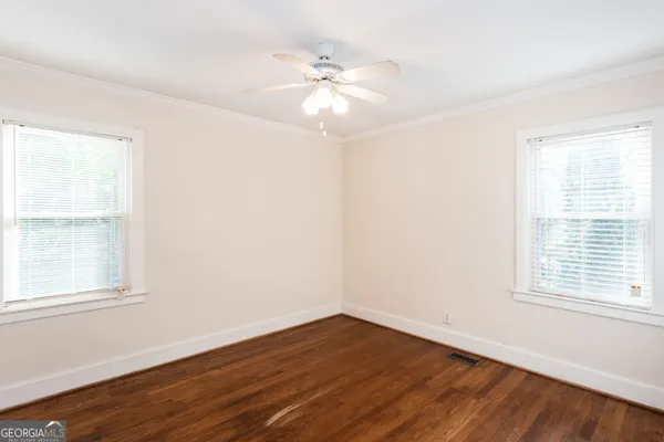 an empty room with wooden floor fan and windows