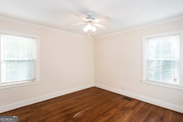 an empty room with wooden floor fan and windows