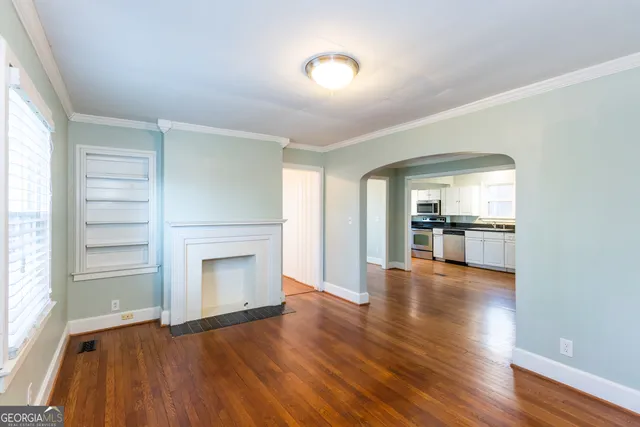 an empty room with wooden floor fireplace and windows
