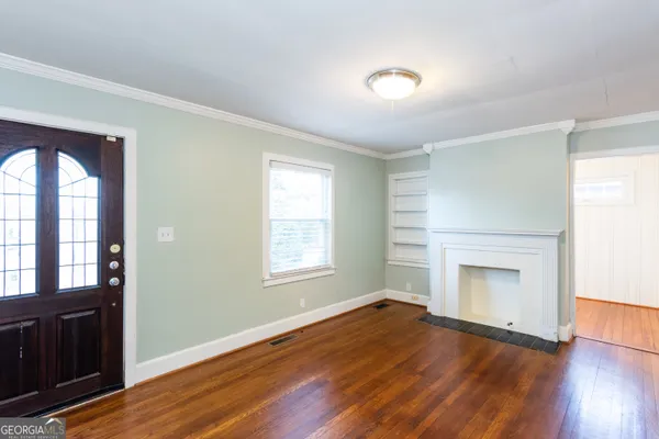 an empty room with wooden floor cabinet and windows