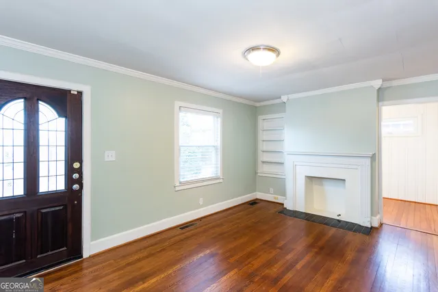 an empty room with wooden floor cabinet and windows