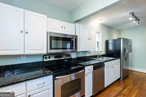 a kitchen with granite countertop a sink stove and refrigerator