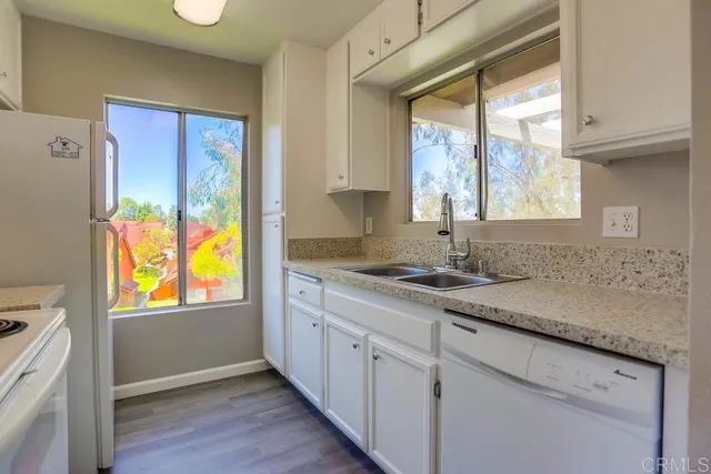 a kitchen with stainless steel appliances granite countertop white cabinets and a large window