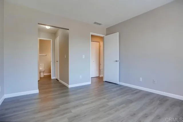 a view of an empty room with wooden floor and closet