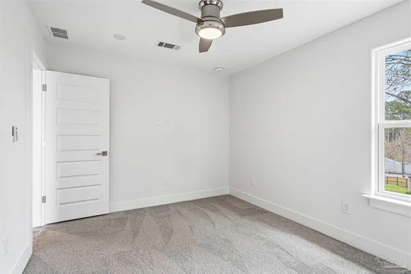 an empty room with windows and ceiling fan