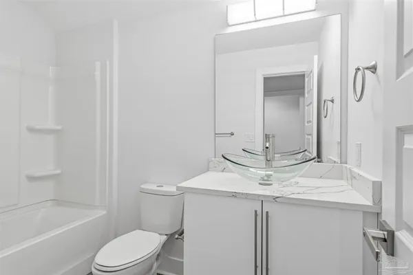a bathroom with a granite countertop sink a toilet and shower